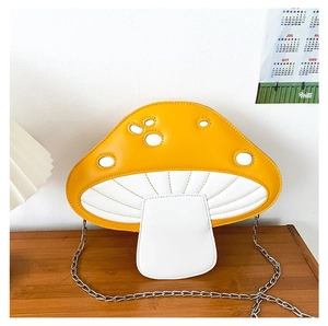 Detail of mushroom crossbody bag showing yellow PU leather and silver chain strap