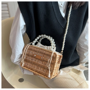 Detailed view of woven straw bag featuring pearl handles and secure drawstring closure