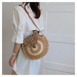 Detail of round straw crossbody bag featuring geometric print flap and metal lock