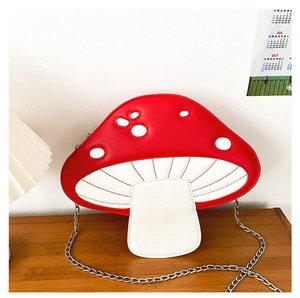 Detail of red and white mushroom crossbody bag with silver chain strap on wooden table