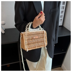 Detail view of woven straw bag with pearl handles, chain strap and drawstring lining