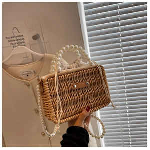 Detail of woven straw bag featuring elegant pearl handle and drawstring canvas lining