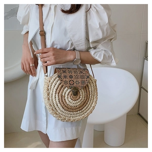 Detailed macro view of the vintage geometric floral pattern on a round straw shoulder bag