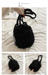Detalle del bolso tipo saco negro tejido a mano con diseño calado y cierre de cordón