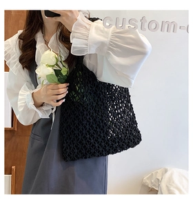 Detail of a black hand-woven mesh tote bag with wide handles for summer holidays