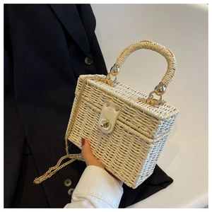 Detail of cream straw box bag with leather flap, gold twist lock and woven top handle