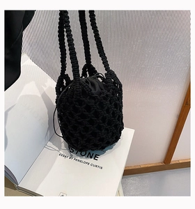 Detalle de bolso saco de algodón trenzado negro con bolsa interior sobre libro blanco