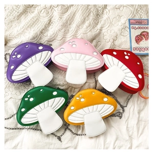 Flat lay of colorful mushroom-shaped crossbody chain bags on white lace fabric background