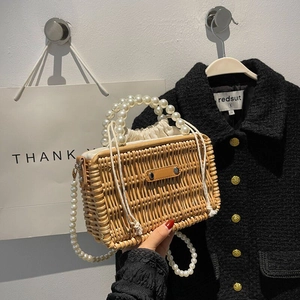 Close-up of handmade straw woven bag with pearl handle and drawstring inner lining