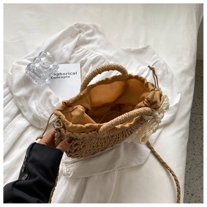 Dettaglio borsa in paglia intrecciata a mano con fiocco di pizzo e fodera con coulisse