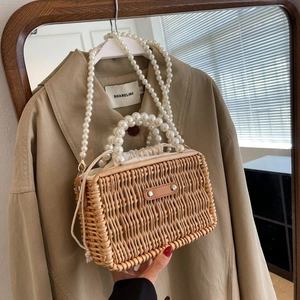 Close-up of handmade straw bag featuring large pearl handles and woven texture detail