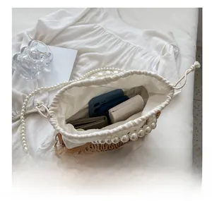 Detail view of woven straw bag interior with drawstring liner and pearl handle