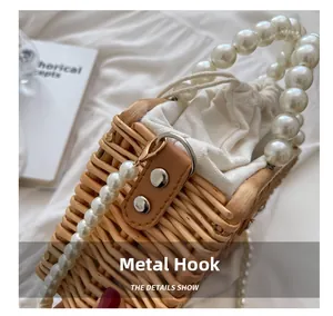 Detail of pearl strap attached with metal lobster clasp to the woven straw beach bag