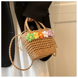Macro detail of hand-woven straw bag featuring colorful crochet flowers and drawstring liner