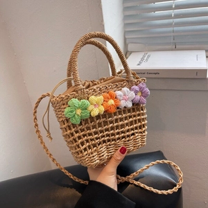 Detail of hand-woven floral straw bag with colorful crochet flowers and drawstring closure