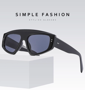 Close-up of futuristic triangle cat-eye sunglasses with silver studs on a white block