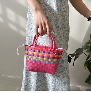 Dettaglio di borsa da spiaggia intrecciata colorata con manici rosa e coulisse