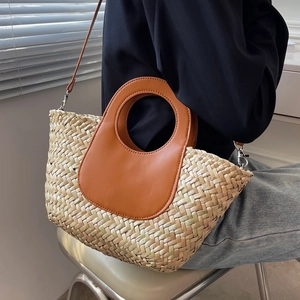 Handmade beige woven straw bucket bag with brown leather handles and detachable shoulder strap