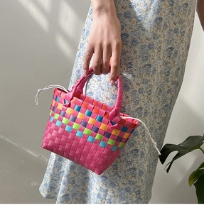 Dettaglio mini borsa a mano intrecciata arcobaleno con coulisse e abito a fiori elegante