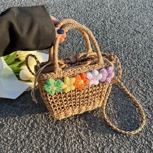 Close-up of handmade straw tote with colorful knit flowers and drawstring closure