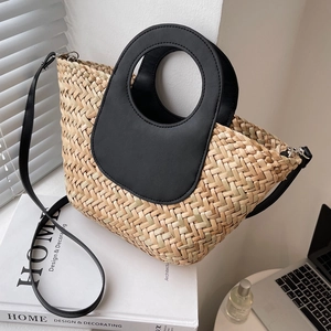 Handcrafted straw bucket bag with black leather round handles and detachable shoulder strap