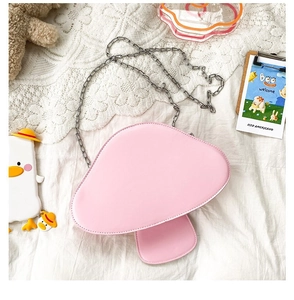 Detail view of pink mushroom crossbody bag with silver metal chain on lace background