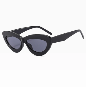 Detail view of retro black cat-eye sunglasses with thick glossy frames and dark lenses