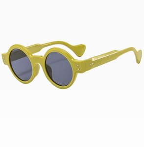 Detail view of round yellow sunglasses featuring unique wavy temples and rivet accents