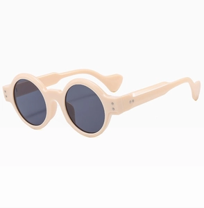 Close-up of beige round punk sunglasses showing metal rivet details and ergonomic temples