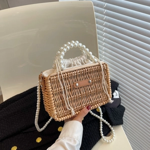 Handcrafted rattan woven beach bag with pearl handles and a crossbody strap for summer