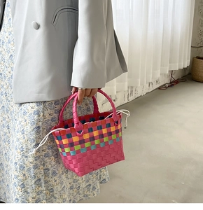 Dettaglio della borsa a cesto intrecciata multicolore con coulisse bianca e doppi manici