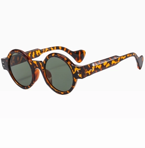 Detail of round punk sunglasses featuring tortoiseshell texture and metal rivets on temples
