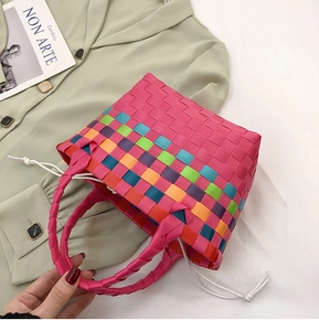 Dettaglio della borsa tote intrecciata arcobaleno su una camicia verde e rivista moda