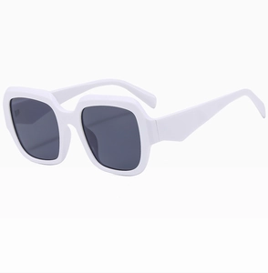 Détail de la large monture blanche brillante et des verres gris foncés des lunettes carrées