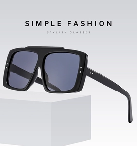 Detail of square black sunglasses with silver rivet accents and blue-grey tinted lenses