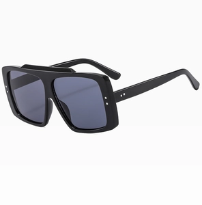 Detail shot of black oversized square sunglasses with thick frames and grey lenses
