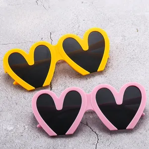 Detailed close-up of heart-shaped sunglasses in vibrant yellow and soft pink plastic frames