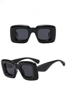 Détail de lunettes de soleil carrées noires avec verres gris et monture épaisse