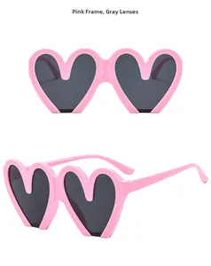 Detail view of pink heart-shaped frame sunglasses with gray lenses and temple structure