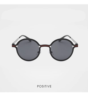 Close-up of round metal sunglasses with red stripe detail and dark polarized lenses