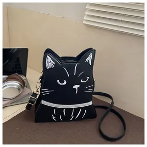 Close-up of black leather cat-shaped crossbody bag with white embroidery and gold hardware