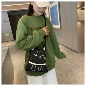 Detail of a black cartoon cat shoulder bag featuring white facial prints and 3D ears