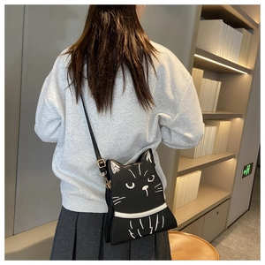 Detailed view of creative cat-shaped black leather crossbody bag on female model