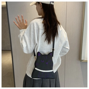 Detail of cute black cat crossbody bag with purple embroidery and adjustable strap