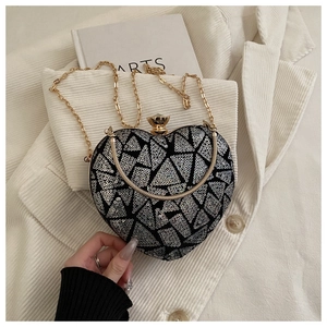 Close-up of heart-shaped evening bag with silver sequins and gold chain strap