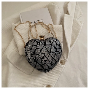 Detailed view of heart-shaped sequin evening bag with gold handle and chain strap