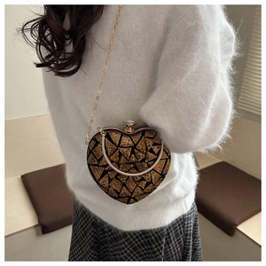 Close-up of heart-shaped gold sequin evening bag with elegant chain strap on a model