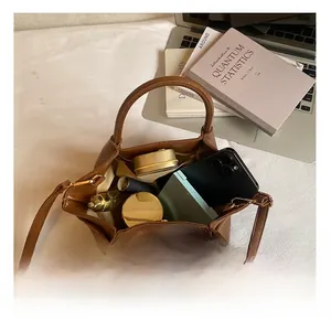 Vue de dessus du sac plissé marron montrant l'intérieur spacieux avec téléphone et maquillage