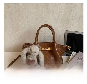 Gros plan du sac en cuir marron texturé avec boucle dorée et porte-clés lapin en peluche