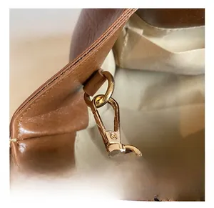 Détail du crochet en métal doré et des coutures sur un sac à main en cuir marron
